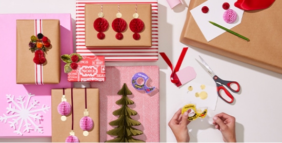 Mãos segurando fita com presentes de Natal ao lado.
