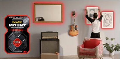 Homem que decora o quarto com fita de montagem Scotch® Mount.
