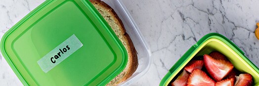 Recipientes de comida com Fita Mágica Scotch® aderida a eles com um nome escrito.
